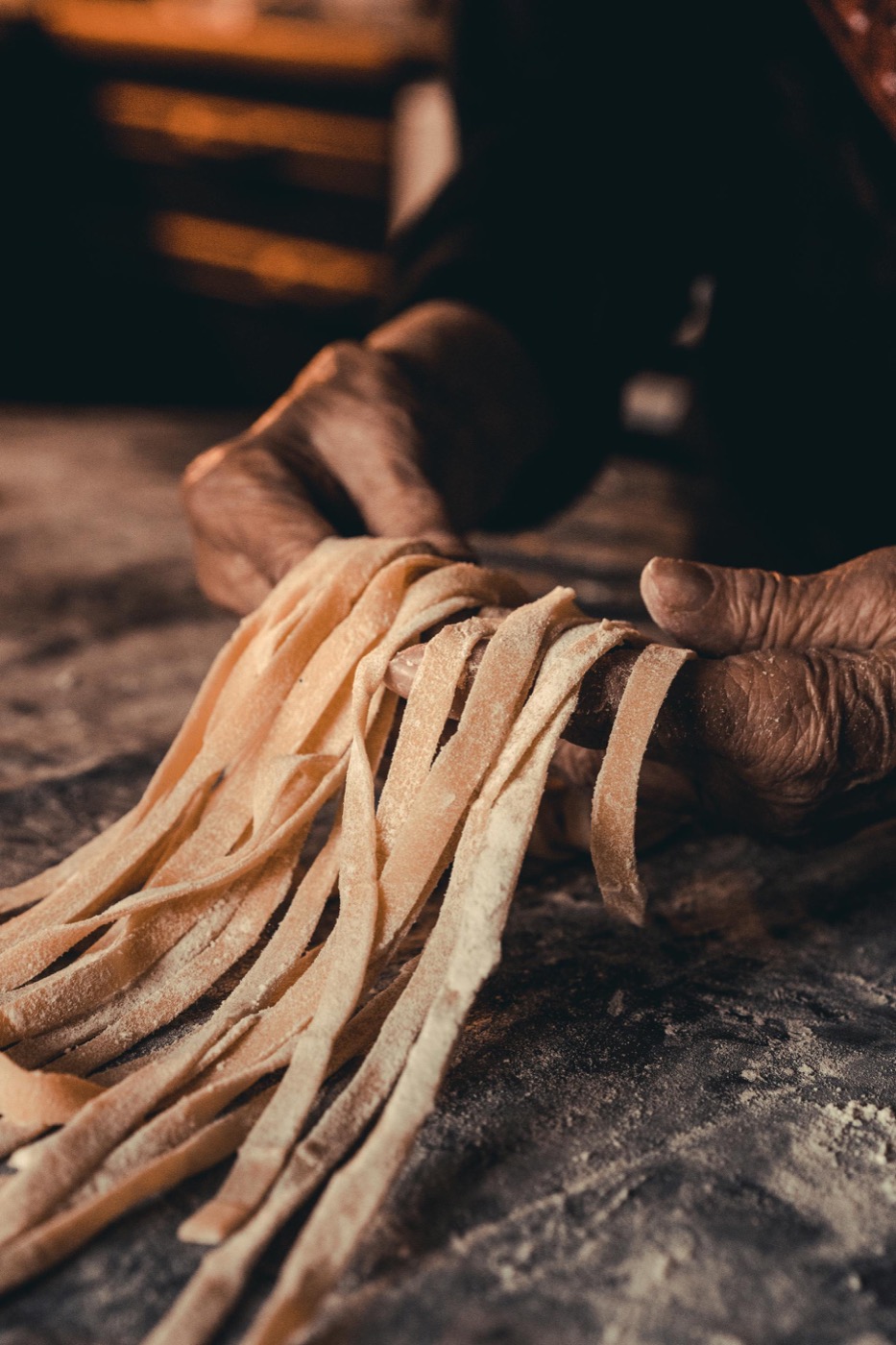 Main qui prélève une farfalle parmi les pâtes fraîches