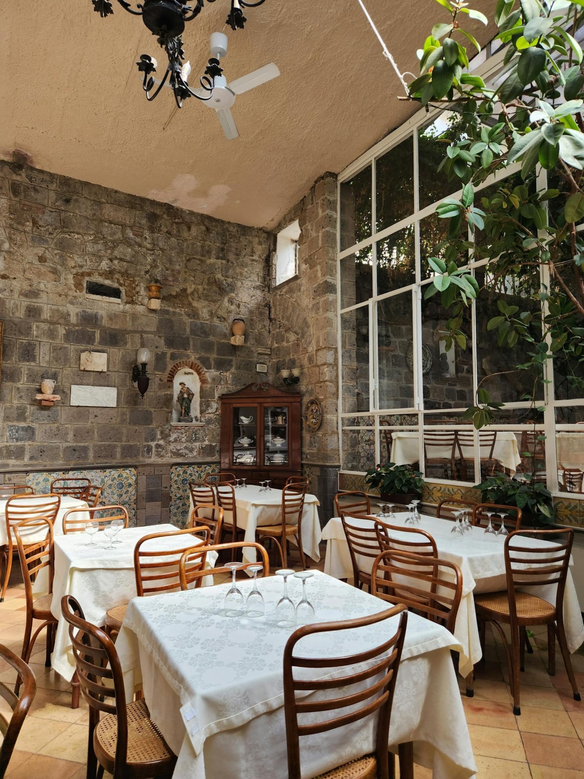 Intérieur trattoria, tables nappées, murs en pierre